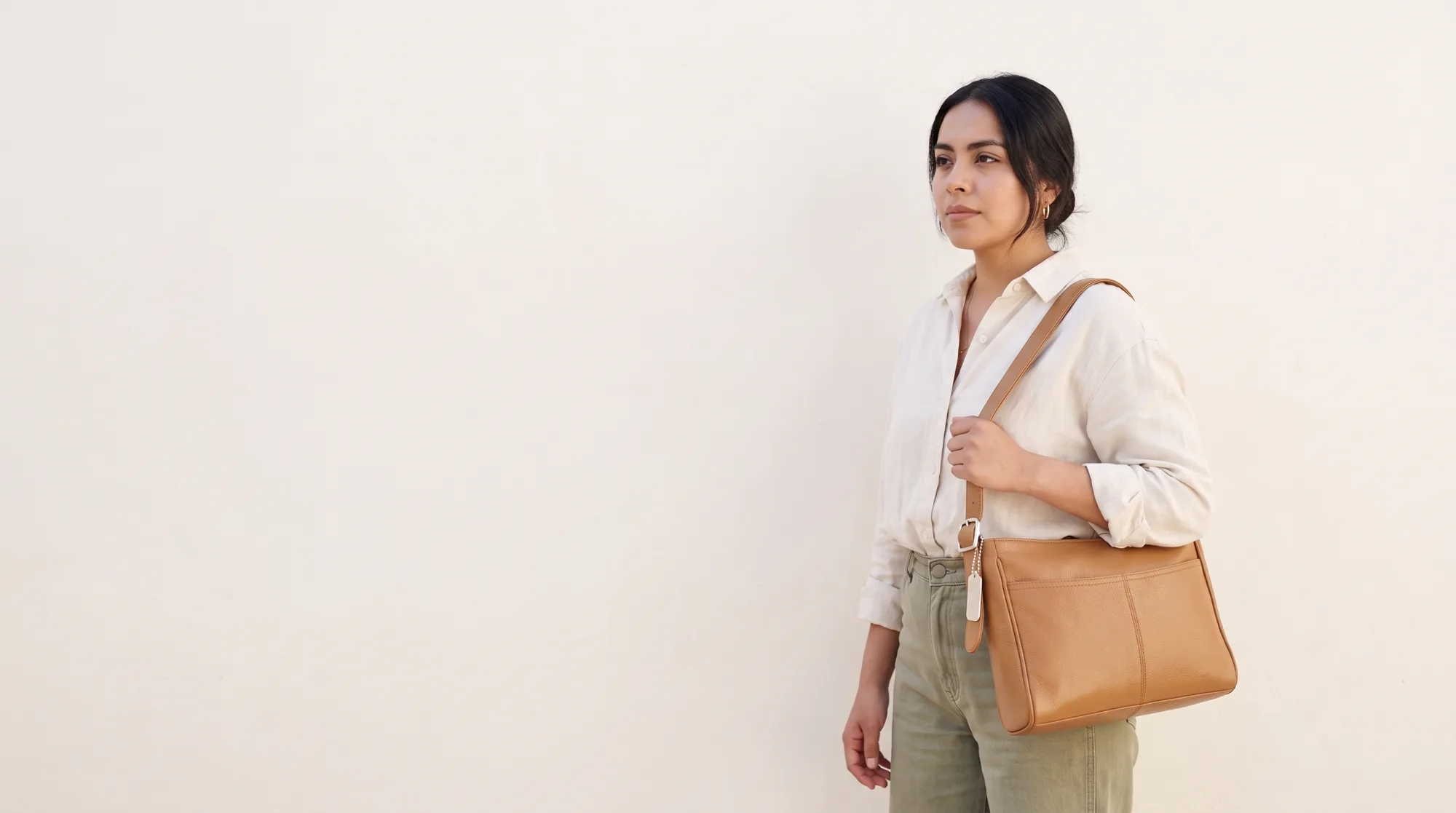 Modelo con bolsa de piel Gino Goganni junto a un muro de cal a pleno sol
